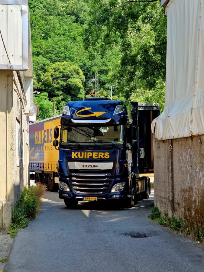 A Kuipers Logistics truck driving through a narrow street in Genoa