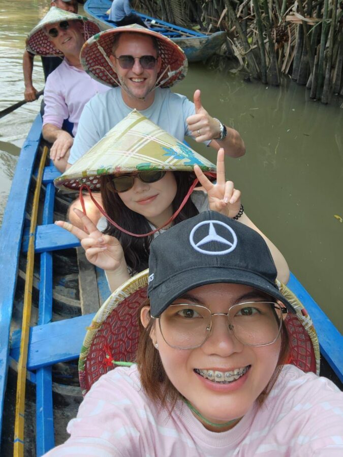 Wouter and Jos sit in a blue boat with their partners from Ho Chi Minh. They’re wearing typical Vietnamese hats.