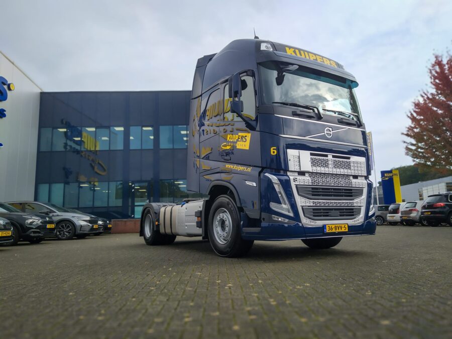 De nieuwe Volvo FH Globetrotter staat schuin voor het pand van Kuipers Logistics. De weespiegeling van het bedrijfspand is nog te zien in de donkerblauwe lak van de vrachtwagen.