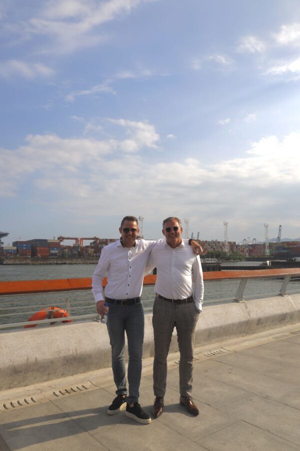 Wouter en Jos staan op de haven kadere met schepen op de achtergrond