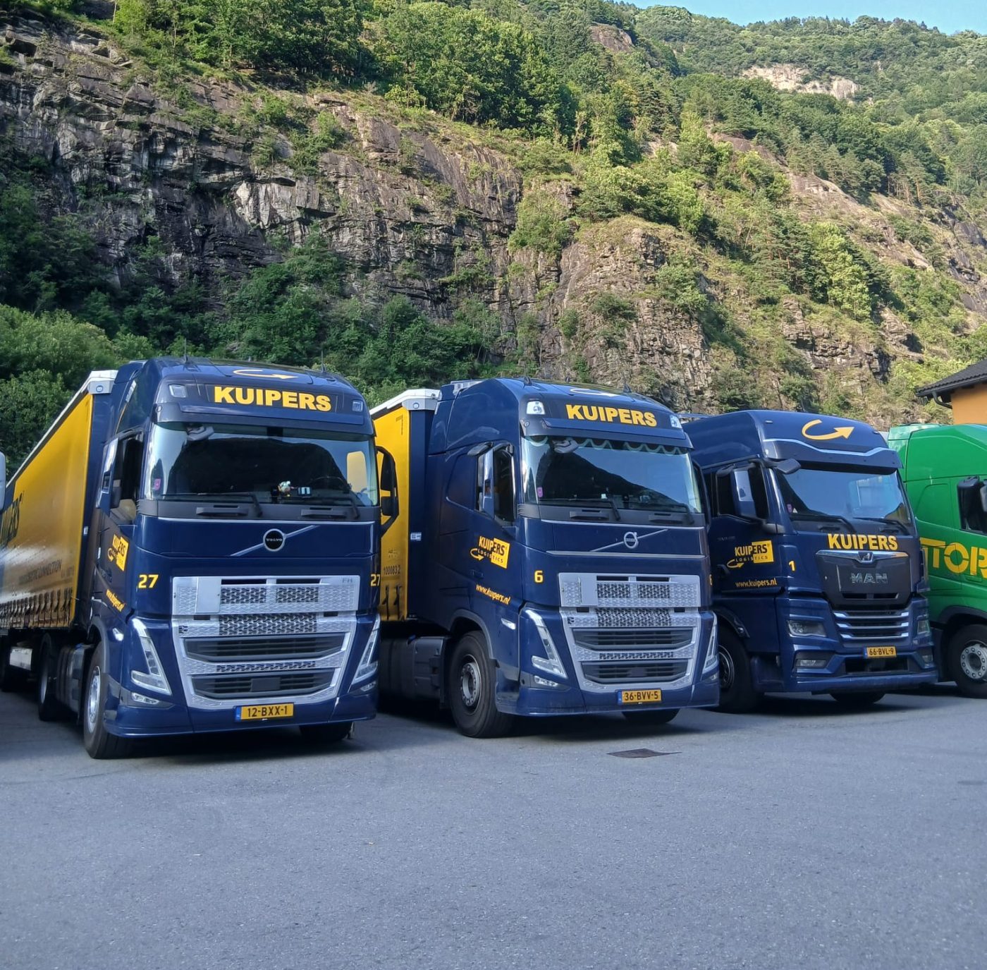 3 Wagens van Kuipers Logistics staan naast elkaar geparkeerd in de bergen.